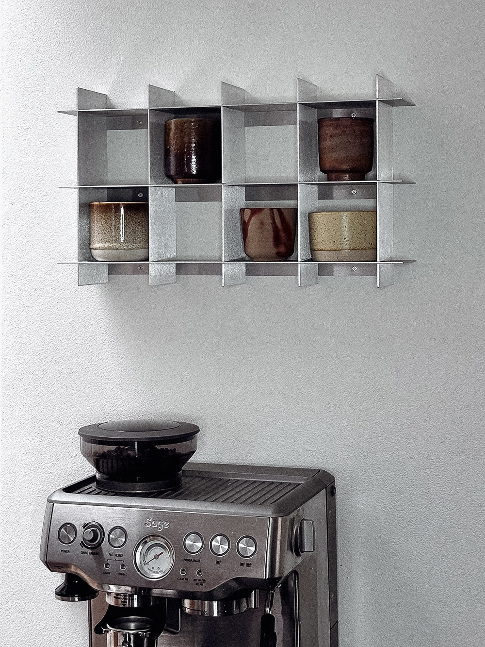 Sættekasse-inspireret væghylde i stål – perfekt til kopper og småting. Klassisk funktion i moderne materialer – sættekasse til kopper i metal.